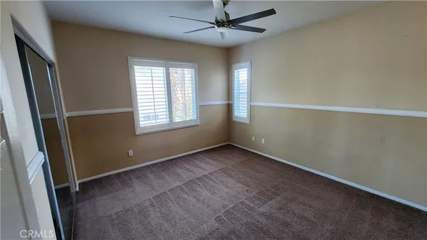 an empty room with windows and fan
