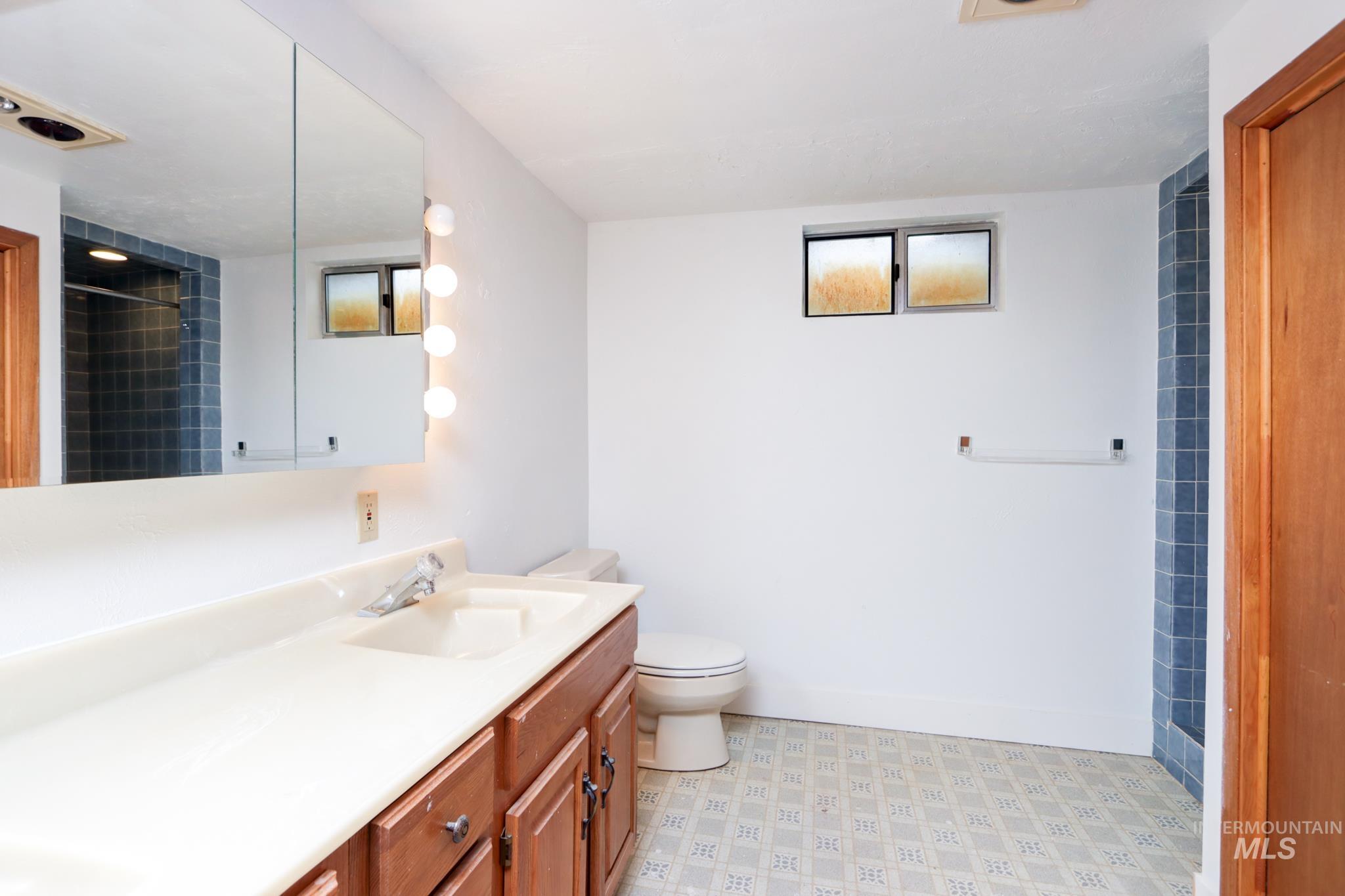 801 Thompson Avenue Nyssa, OR 97913 - Photo 30 of 46 Bathroom featuring a wood-finish vanity with integrated sink, a large mirrored medicine cabinet, and sconce lighting