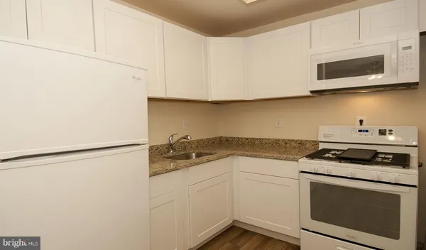 a kitchen with stainless steel appliances granite countertop white cabinets a stove a microwave and a refrigerator