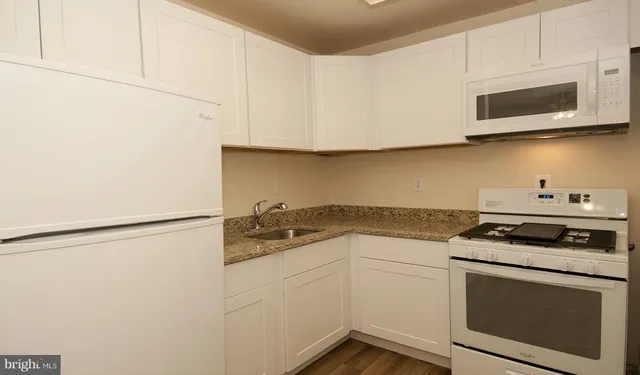 a kitchen with stainless steel appliances granite countertop white cabinets a stove a microwave and a refrigerator