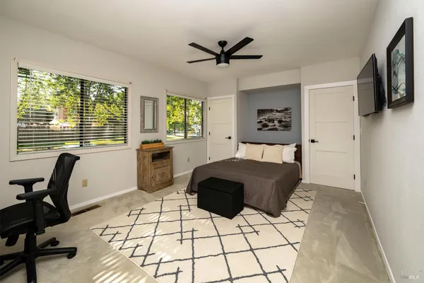 a bedroom with a bed a desk and chair with window