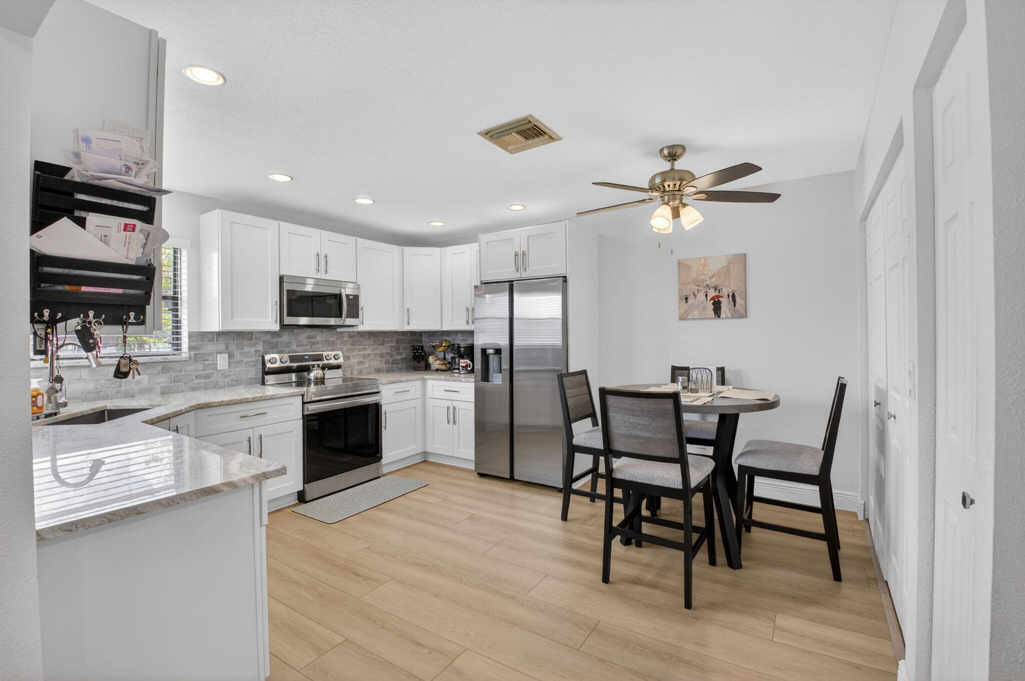 2360 Northwest 12th Street Delray Beach, FL 33445 - Photo 12 of 62 a kitchen with stainless steel appliances kitchen island granite countertop a dining table chairs and a refrigerator