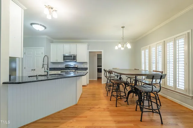 a kitchen with stainless steel appliances granite countertop wooden floor dining table and chairs