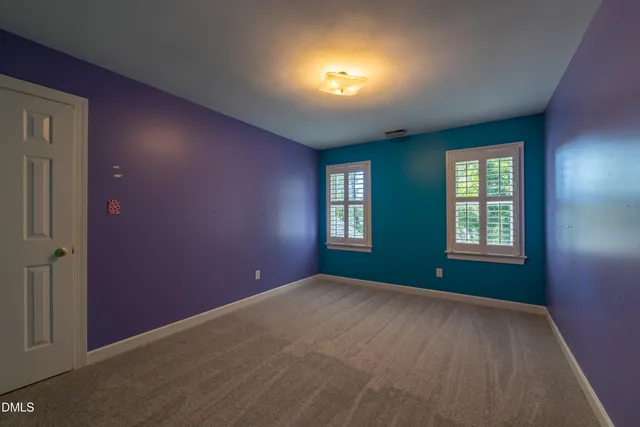 an empty room with windows and chandelier fan