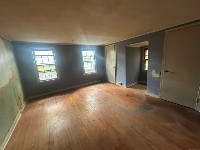 an empty room with wooden floor and windows
