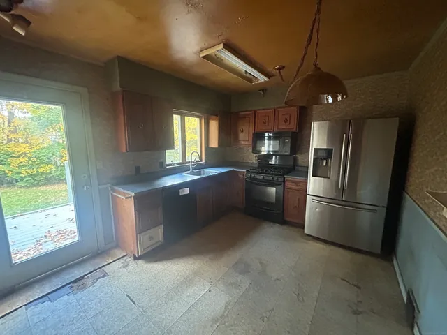 a kitchen with stainless steel appliances granite countertop a refrigerator a sink a stove and white cabinets with wooden floor