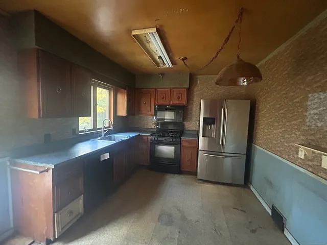 a kitchen with stainless steel appliances granite countertop a refrigerator a sink dishwasher a stove and a refrigerator