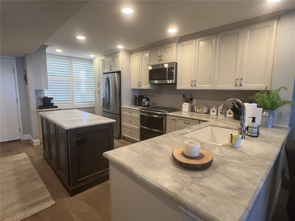 7100 Sunset Way, Unit PH5 St. Pete Beach, FL 33706 - Photo 11 of 32 a kitchen with stainless steel appliances granite countertop a sink a stove and a refrigerator