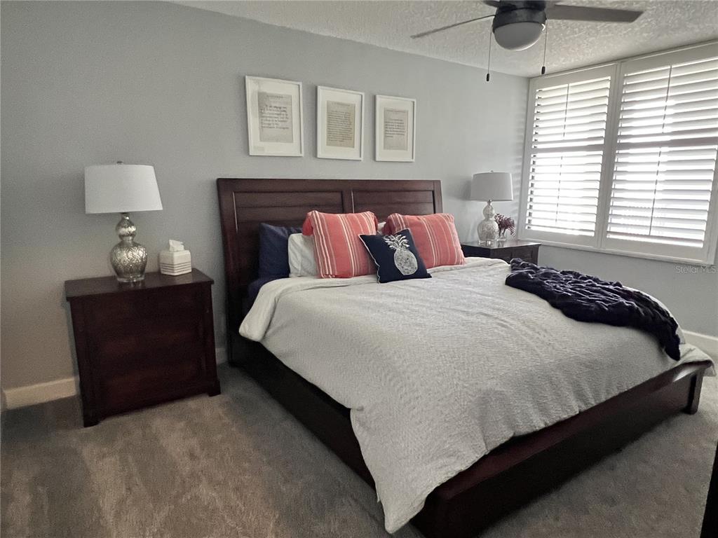7100 Sunset Way, Unit PH5 St. Pete Beach, FL 33706 - Photo 19 of 32 a large bed sitting in a bedroom next to a window and a lamp