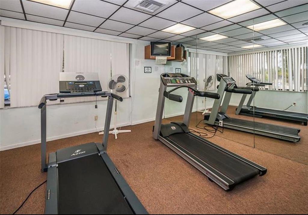 7100 Sunset Way, Unit PH5 St. Pete Beach, FL 33706 - Photo 28 of 32 a room with gym equipment and a table