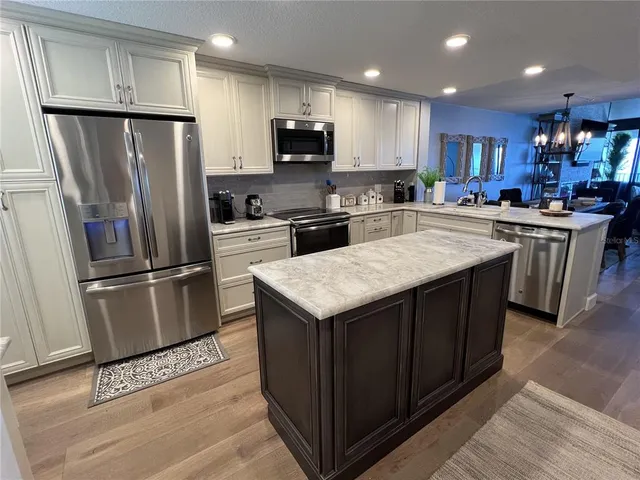 a kitchen with stainless steel appliances granite countertop a sink a stove and a refrigerator