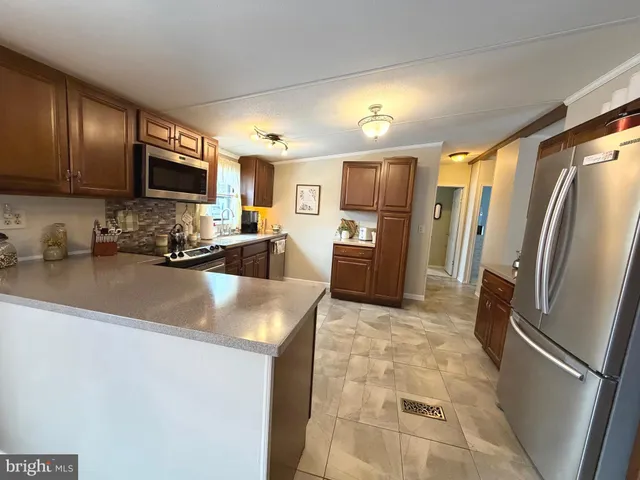 a view of a kitchen with kitchen island a counter top space a sink cabinets and stainless steel appliances