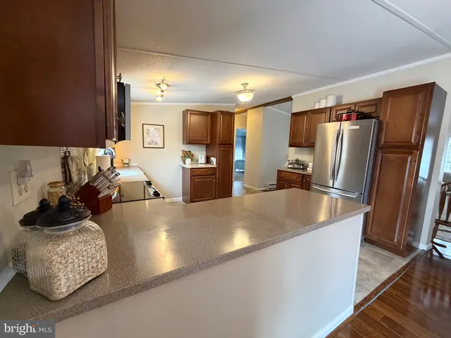 a large kitchen with a refrigerator a stove a sink a dining table and chairs with wooden floor