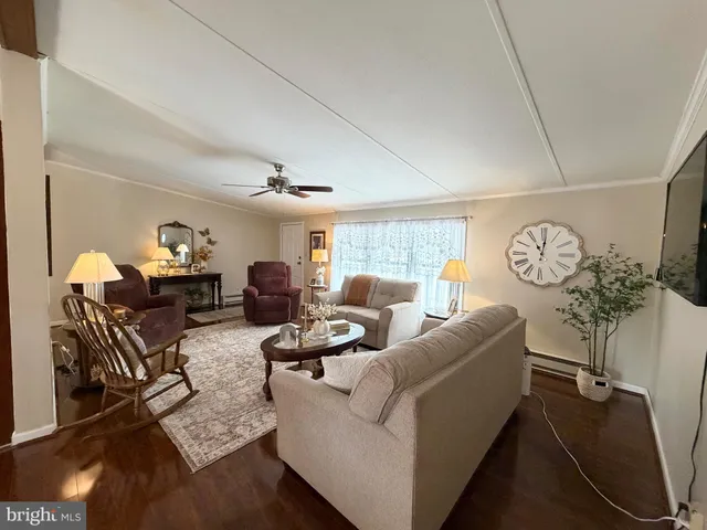 a living room with furniture kitchen view and a wooden floor