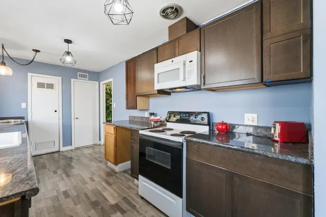 a kitchen with stainless steel appliances granite countertop a stove a sink and a microwave