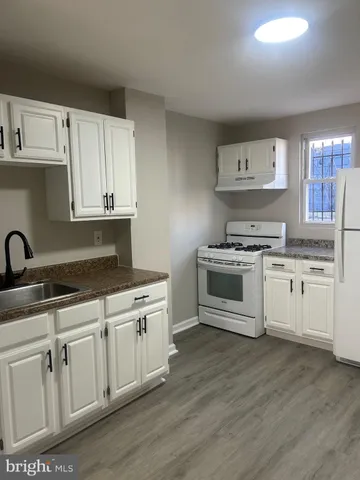 a white kitchen with stainless steel appliances granite countertop a stove a sink and white cabinets
