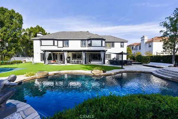 a view of pool with lawn chairs and large trees