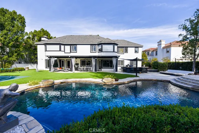a view of pool with lawn chairs and large trees