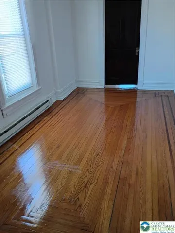 a view of an empty room with wooden floor and a window