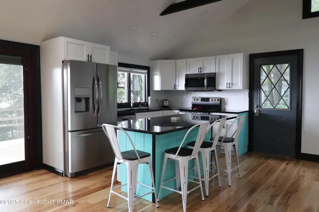 a kitchen with stainless steel appliances granite countertop a refrigerator a stove a microwave oven a sink and a dining table with garden view