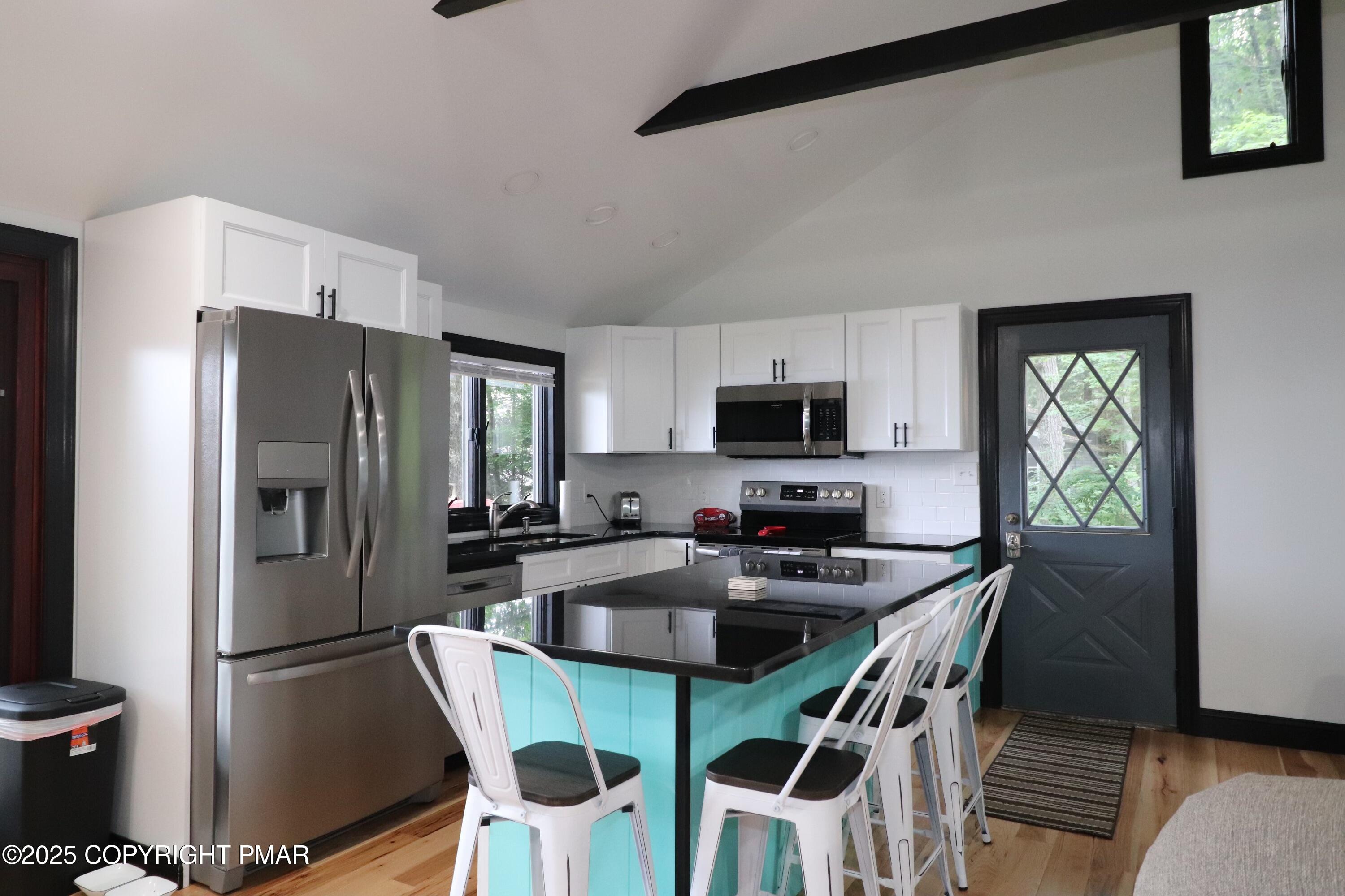 101 Antler Rdg Court Hawley, PA 18428 - Photo 19 of 36 a kitchen with stainless steel appliances granite countertop a refrigerator a stove a microwave oven a sink and a dining table with garden view