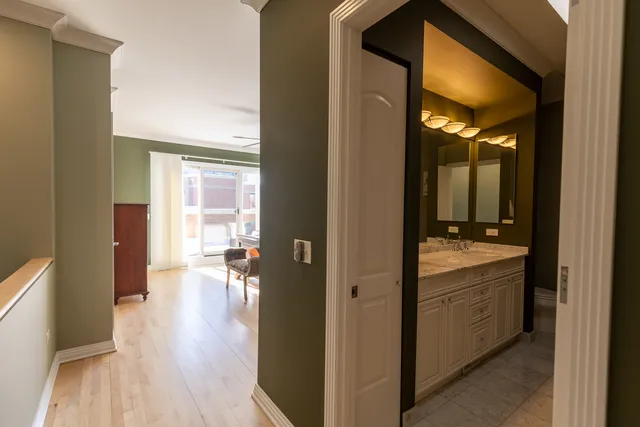 a view of a hallway with wooden floor and a bathroom