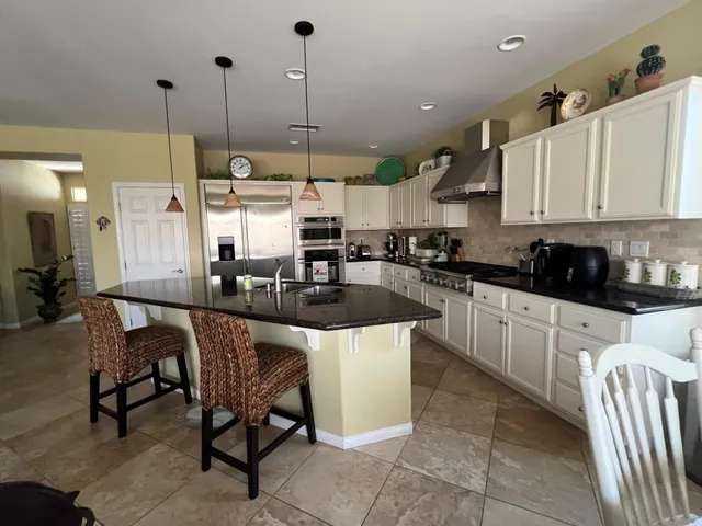 a kitchen with stainless steel appliances granite countertop a stove a sink a kitchen island with a dining table and chairs