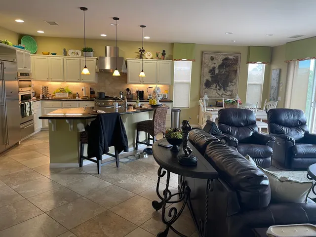 a living room with furniture kitchen view and a chandelier
