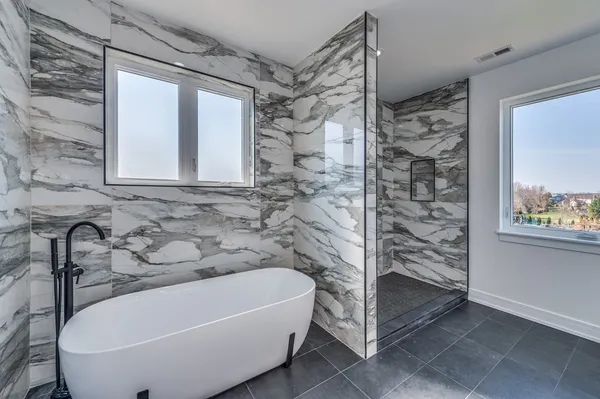 a bathroom with a tub a window and a shower