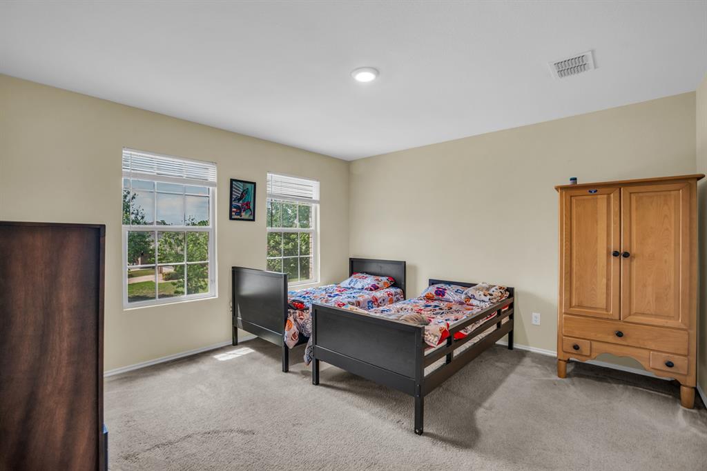 5718 Green Ivy Road Denton, TX 76210 - Photo 24 of 37 Light-filled room featuring two large windows with blinds, neutral-toned walls, and carpet flooring
