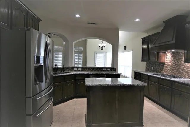 a kitchen with stainless steel appliances granite countertop a refrigerator a sink and a stove