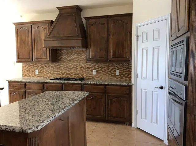 a kitchen with granite countertop a sink dishwasher stove and cabinets