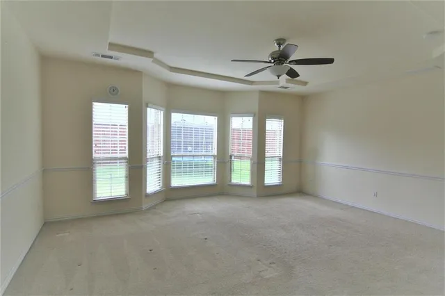 an empty room with windows and ceiling fan