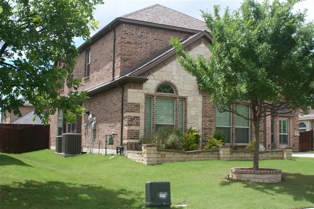 a backyard of a house with table and chairs potted plants and a large tree