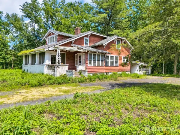 a view of a house with a small yard plants and large tree