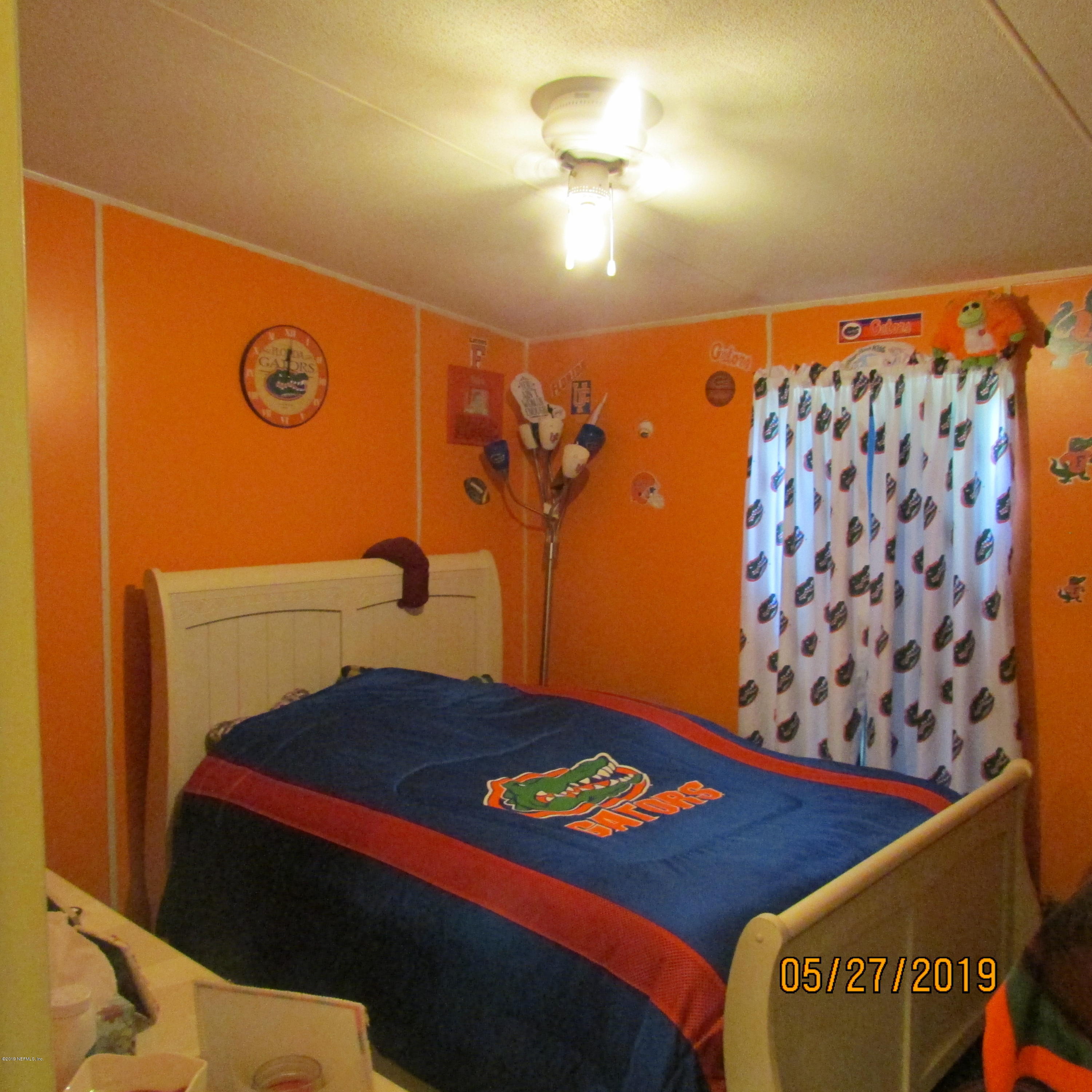 986 Bea Lane Jacksonville, FL 32220 - Photo 38 of 42 a bedroom with a bed and a lamp on the dresser