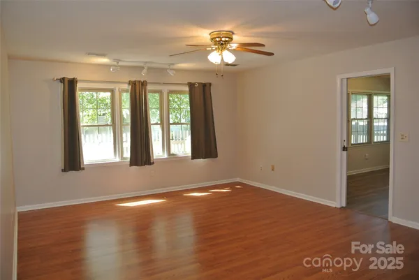 a view of an empty room with window and wooden floor