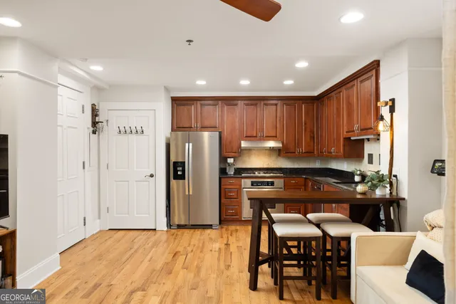 a kitchen with granite countertop a refrigerator a stove a sink a dining table and chairs