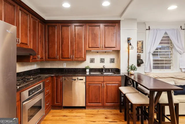 a kitchen with stainless steel appliances granite countertop a stove top oven a sink dishwasher and cabinets with wooden floor