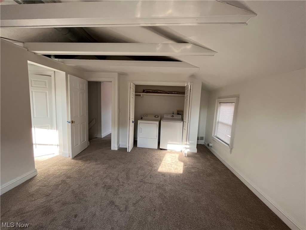 1697 Fulton Road Cleveland, OH 44113 - Photo 23 of 23 Unfurnished bedroom featuring vaulted ceiling with beams, a closet, separate washer and dryer, and dark carpet