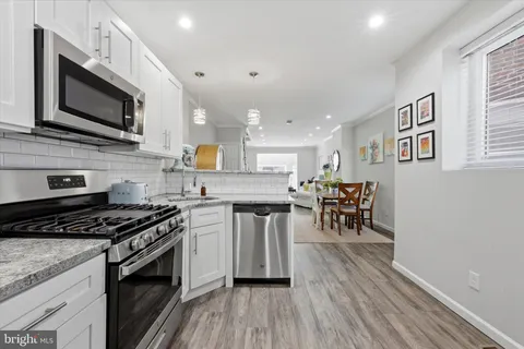 a kitchen with stainless steel appliances a kitchen island hardwood floor sink stove dining table and chairs