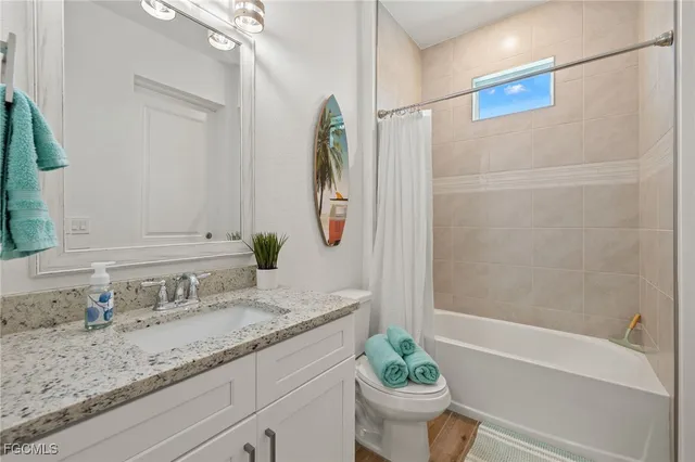 a bathroom with a granite countertop sink a toilet and shower