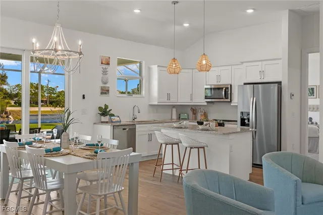 a kitchen with stainless steel appliances granite countertop a stove a refrigerator a kitchen island a dining table and chairs