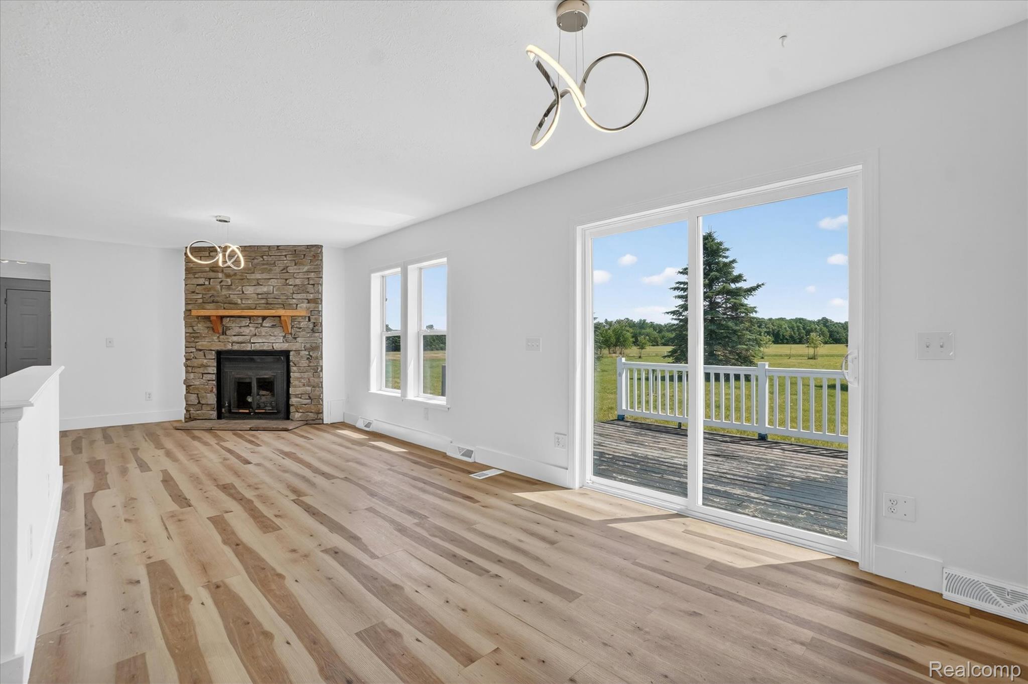 1400 North Every Road Mason, MI 48854 - Photo 3 of 33 Spacious interior featuring wood-finish flooring, a stone-clad fireplace with a wood mantle, and white walls