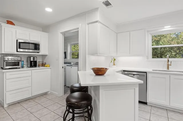a kitchen with cabinets appliances a sink and a window