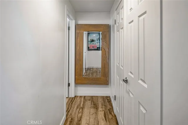 a view of a hallway with wooden floor and a bathroom