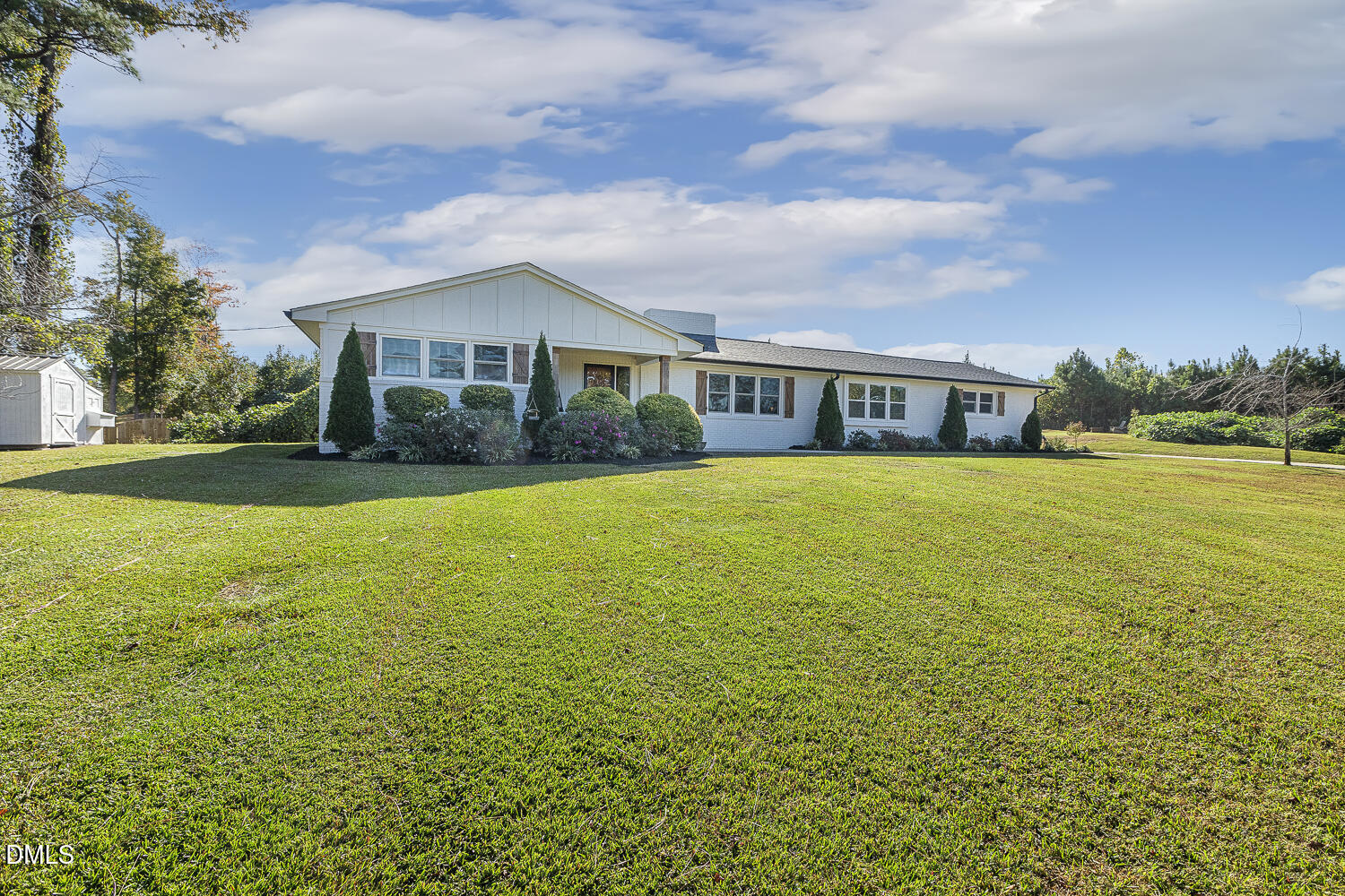 a view of a house with a big yard and large trees