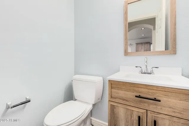 a bathroom with a granite countertop toilet sink and mirror