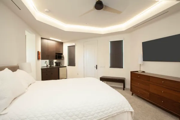 a large bedroom with a bed and a flat tv screen on dresser