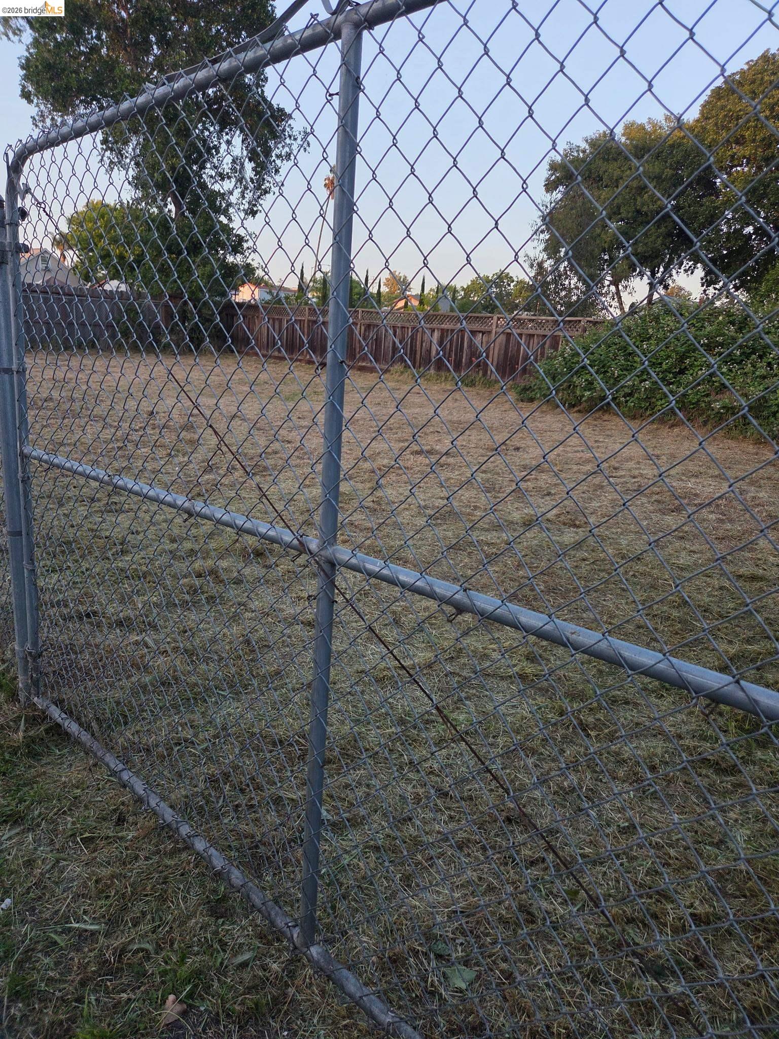 462 Springs Road Vallejo, CA 94590 - Photo 8 of 9 Chain-link fence enclosing an outdoor space with a natural ground cover and surrounding wood fencing